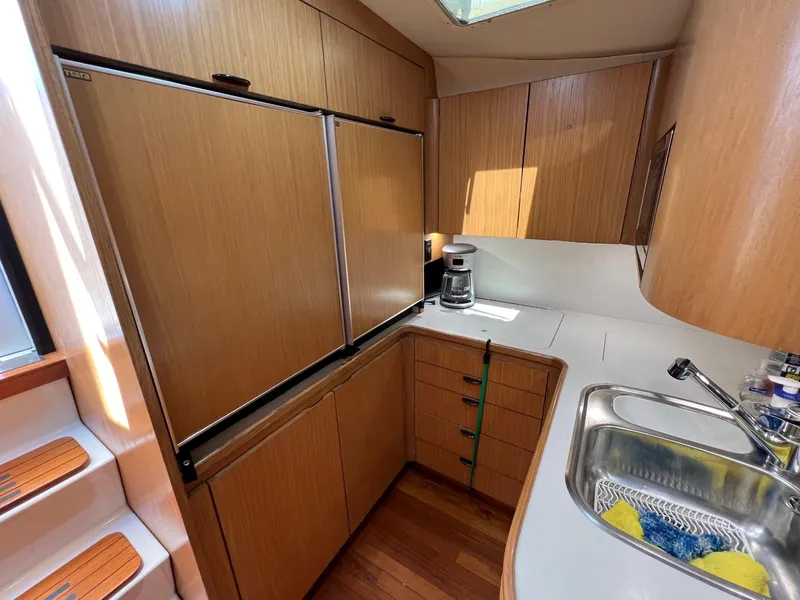 Slide: The Image of 1996 Tiara Yachts 4300 Open galley with wood cabinets, sink, and refrigerator. - 26