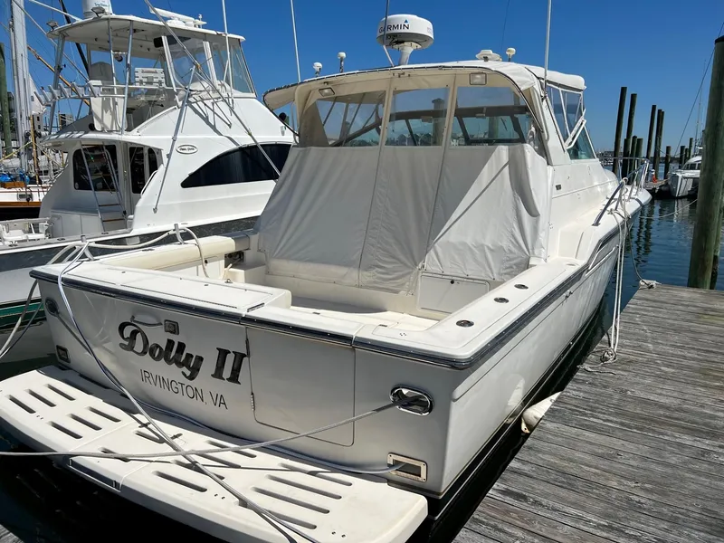 Slide: The Image of 1996 Tiara Yachts 4300 Open docked, featuring covered seating and sleek design. - 4