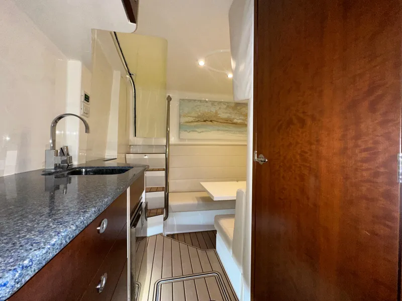 Slide: The Image of 2015 SeaVee 43 Fish-Around interior with kitchenette, seating area, and wooden cabinetry. - 68