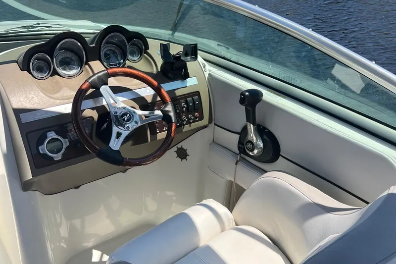 Slide: The Image of 2012 Sea Ray 260 Sundeck helm with steering wheel and control panel, on calm water. - 22