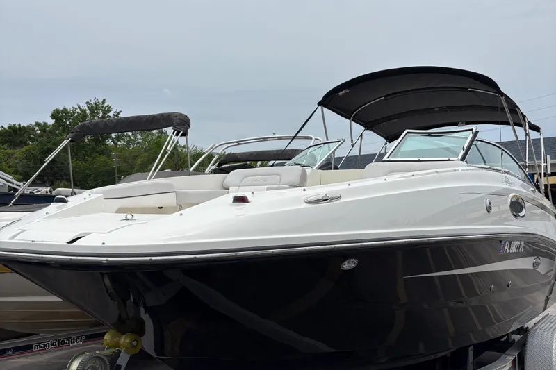 Slide: The Image of 2012 Sea Ray 260 Sundeck boat with black hull and canopy, docked outdoors. - 9