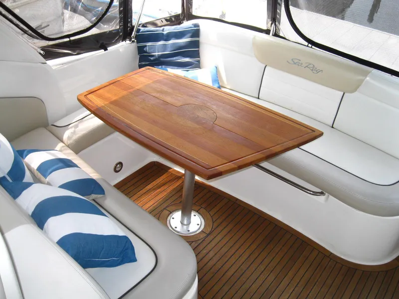 Slide: The Image of 2011 Sea Ray 350 Sundancer interior with wooden table, white seating, and striped cushions. - 11