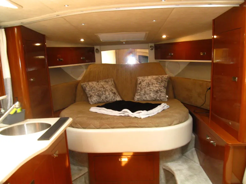Slide: The Image of 2011 Sea Ray 350 Sundancer cabin interior with bed, pillows, and wooden cabinetry. - 28