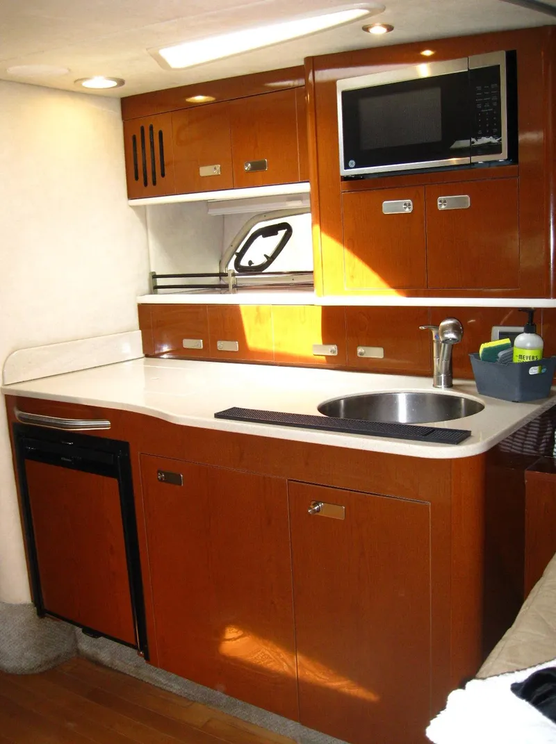 Slide: The Image of 2011 Sea Ray 350 Sundancer kitchen with wood cabinets, sink, microwave, and compact fridge. - 34