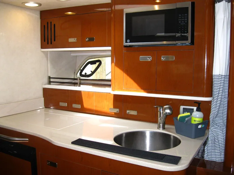 Slide: The Image of 2011 Sea Ray 350 Sundancer kitchen with sink, microwave, and wooden cabinetry. - 36