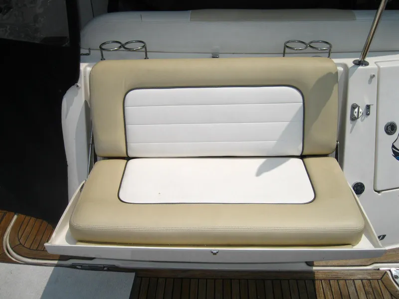 Slide: The Image of 2011 Sea Ray 350 Sundancer boat seat with beige and white cushions, cup holders, and teak flooring. - 5
