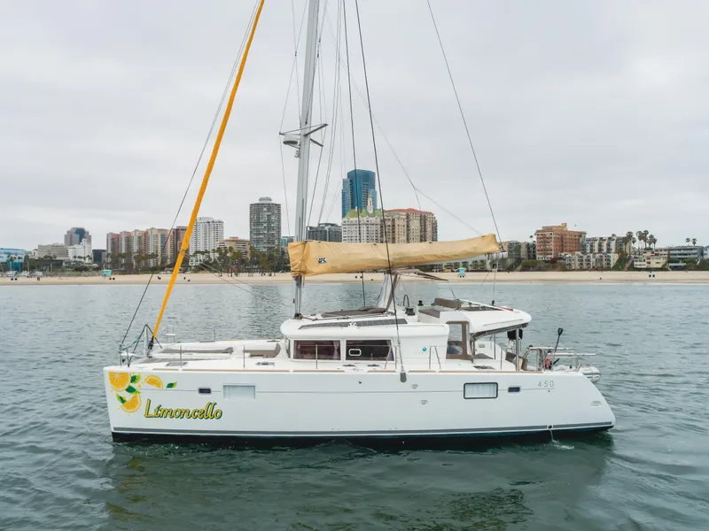 Slide: The Image of 2016 Lagoon 450F catamaran named "Limoncello" sailing near a city skyline. - 14