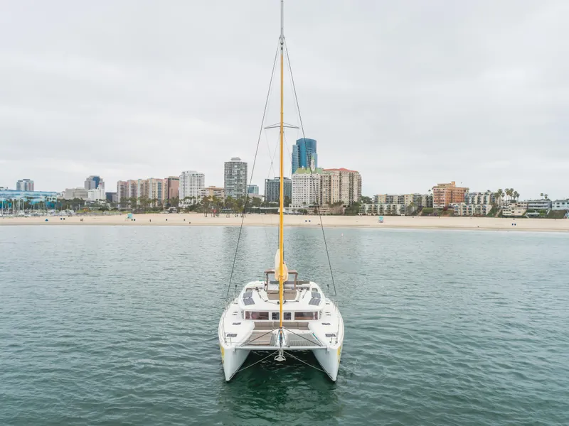 Slide: The Image of 2016 Lagoon 450F catamaran on calm water with city skyline in background. - 16
