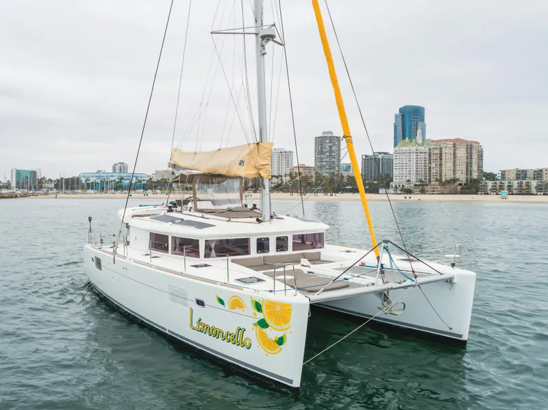 Slide: The Image of 2016 Lagoon 450F catamaran sailing near urban skyline, featuring "Limoncello" design on hull. - 8
