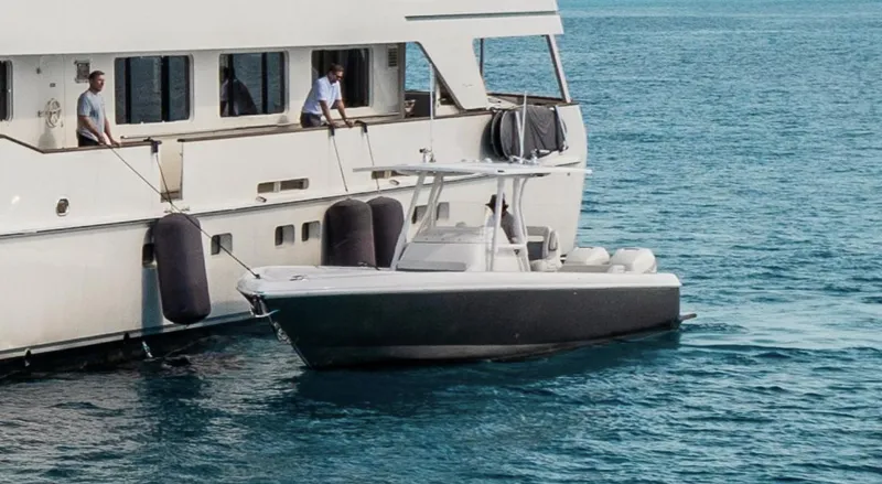 The Image of 2016 Intrepid 327 Center Console boat docked beside a larger yacht on calm water. - 0