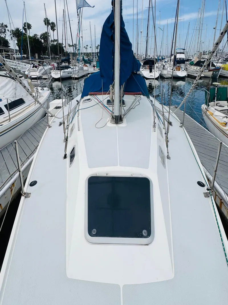 Slide: The Image of 1994 Catalina 320 sailboat docked in a marina, surrounded by other boats. - 11