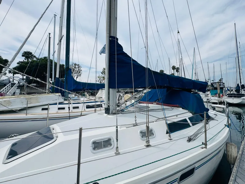 Slide: The Image of 1994 Catalina 320 sailboat docked in marina, featuring blue sail cover. - 12