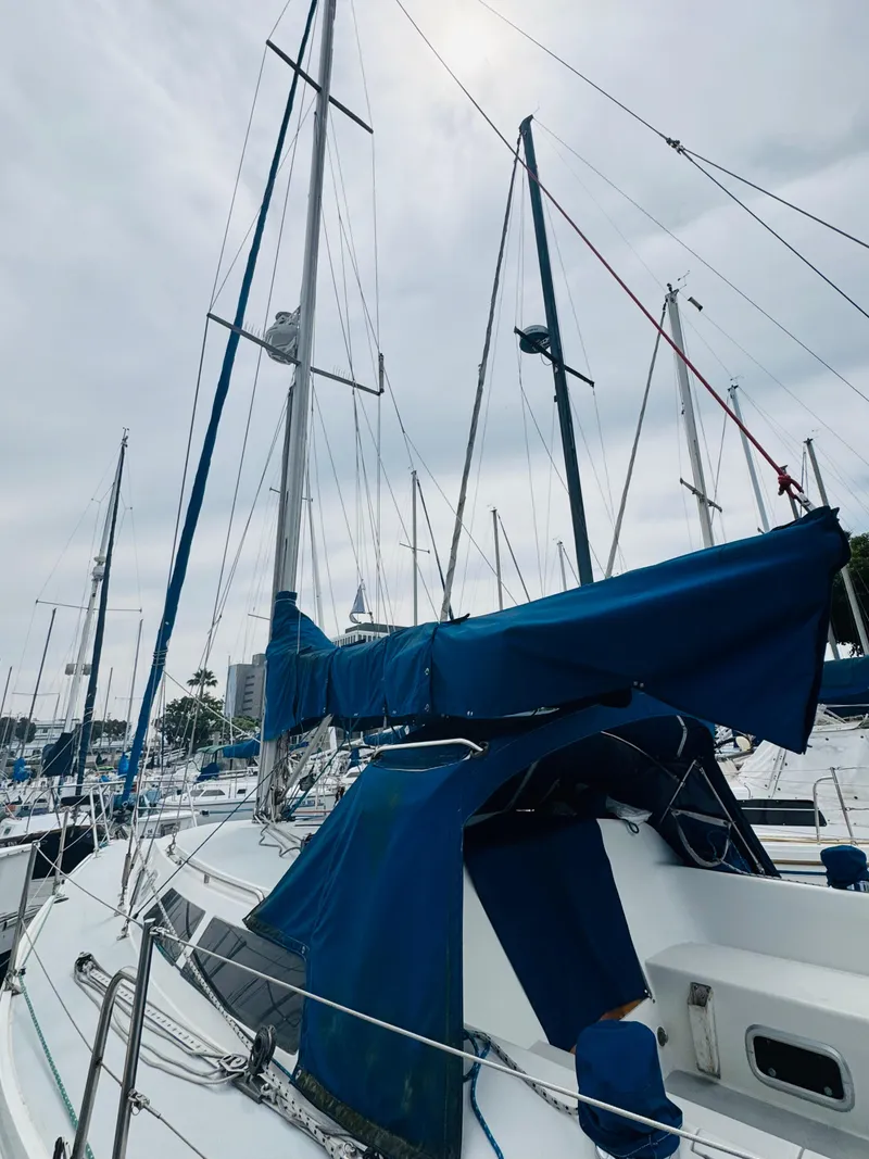 Slide: The Image of 1994 Catalina 320 sailboat with blue covers docked at a marina. - 16
