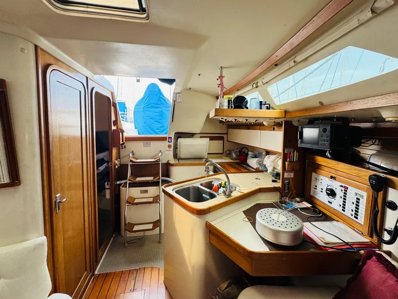 Slide: The Image of Interior of a 1994 Catalina 320 sailboat, featuring a compact kitchen and navigation area. - 21