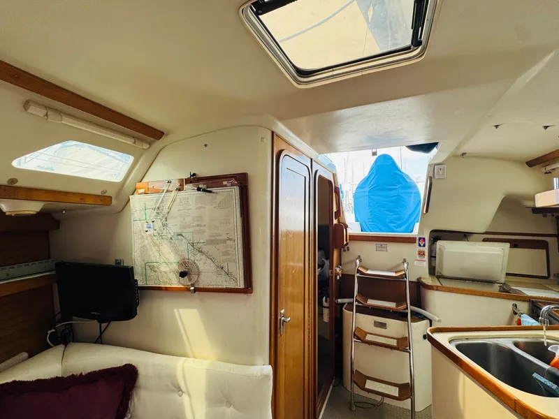 Slide: The Image of Interior of a 1994 Catalina 320 sailboat, featuring a cozy cabin with a map and seating. - 22