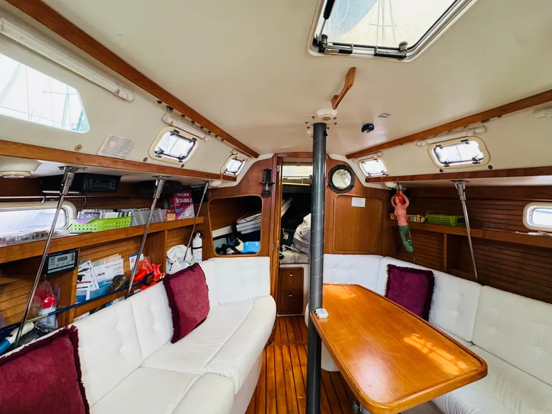 Slide: The Image of Interior of a 1994 Catalina 320 sailboat with white seating and wooden table. - 26