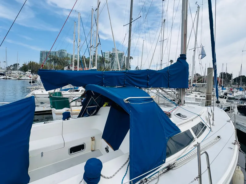 Slide: The Image of 1994 Catalina 320 sailboat docked in marina, featuring blue covers and clear sky. - 8