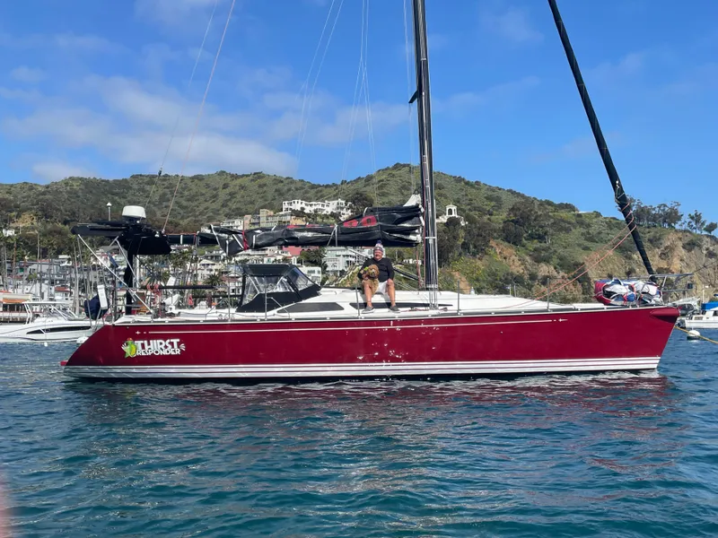 Slide: The Image of Red C&C 121 sailboat from 2001 on water, with hills and buildings in background. - 3