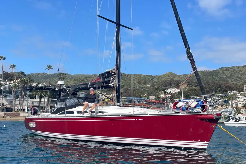 Slide: The Image of Red C&C 121 sailboat from 2001 on calm water near a coastal town. - 4
