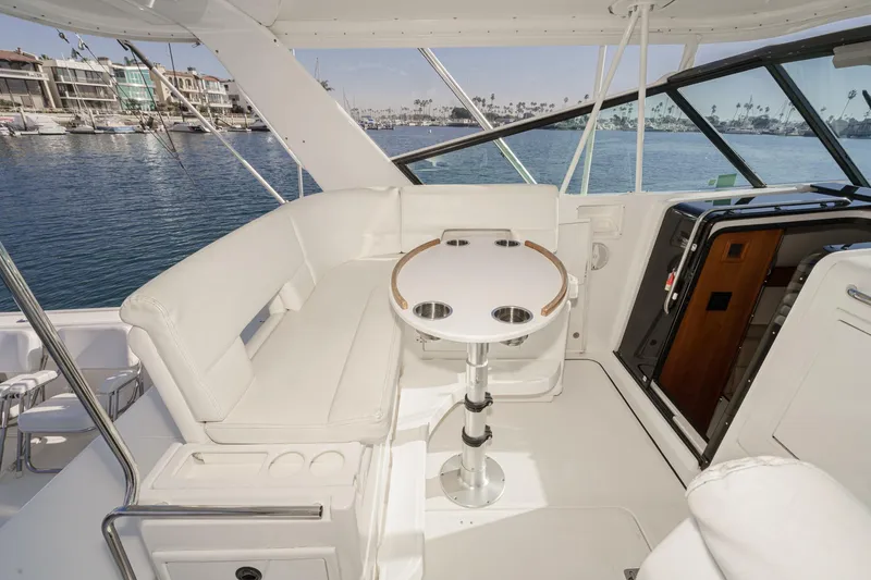 Slide: The Image of 2002 Tiara Yachts 4100 Open interior with white seating and round table, docked by waterfront. - 17