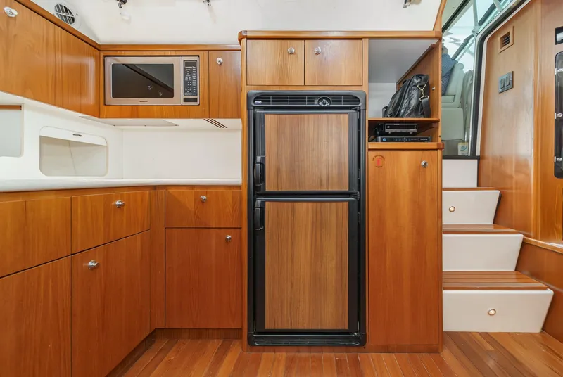 Slide: The Image of 2002 Tiara Yachts 4100 Open interior with wood cabinetry, fridge, microwave, and stairs. - 20
