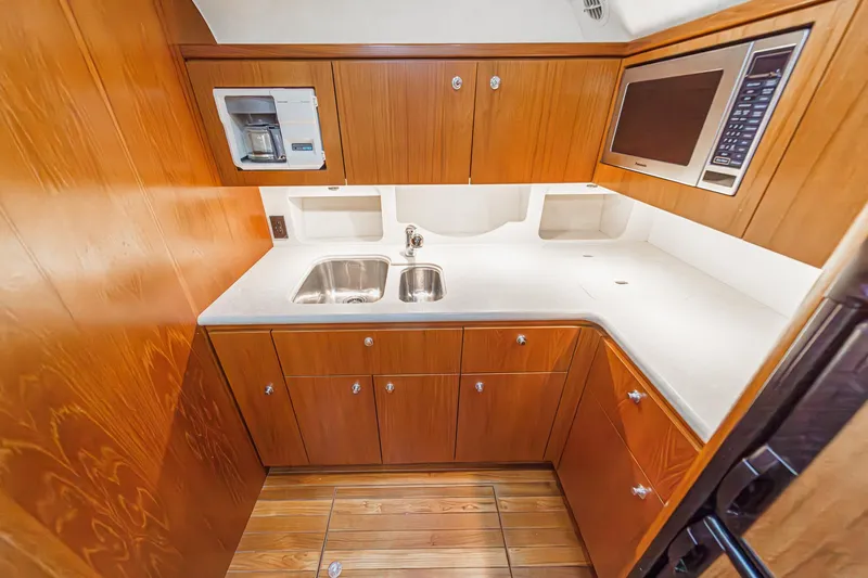 Slide: The Image of 2002 Tiara Yachts 4100 Open galley with wood cabinetry, stainless steel sink, and appliances. - 22