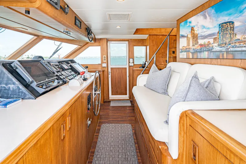 Slide: The Image of 1996 Hatteras 70 Sport Deck Motor Yacht interior with helm, seating, and cityscape artwork. - 13