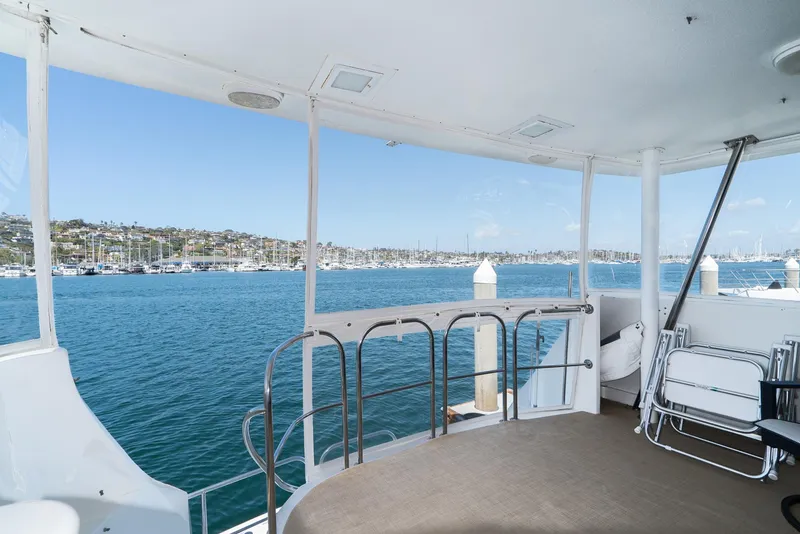 Slide: The Image of 1996 Hatteras 70 Sport Deck Motor Yacht with marina view, featuring spacious deck and seating. - 38