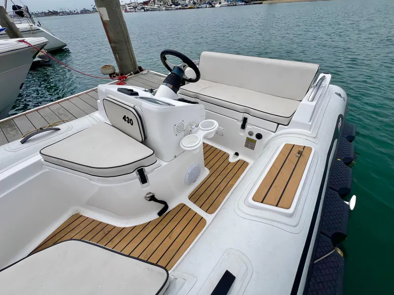 Slide: The Image of 2023 AB Inflatables ABJET 430XP boat interior with seating and steering, docked by the water. - 10