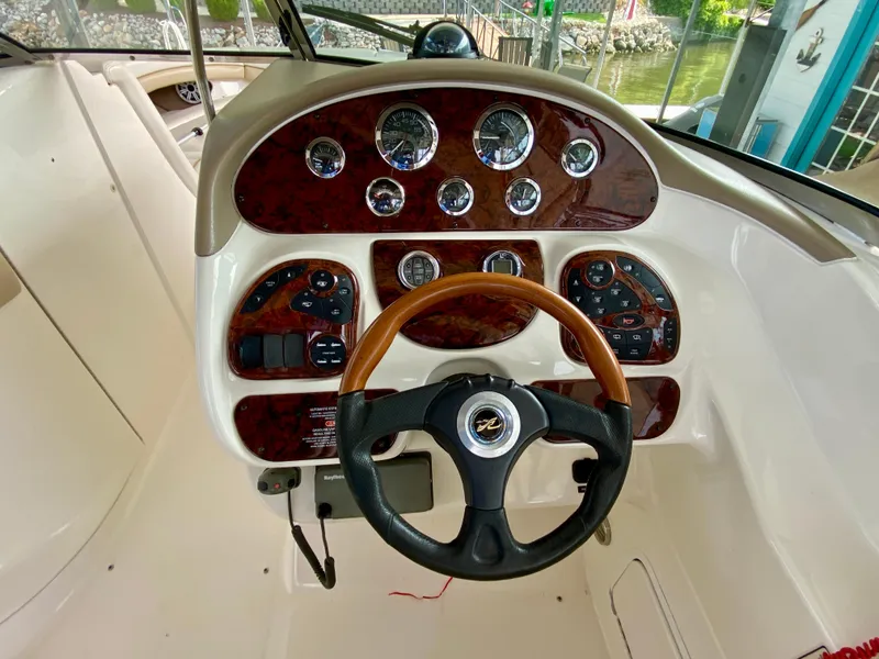 Slide: The Image of 2001 Sea Ray 290 Bowrider dashboard with wood accents and steering wheel. - 16