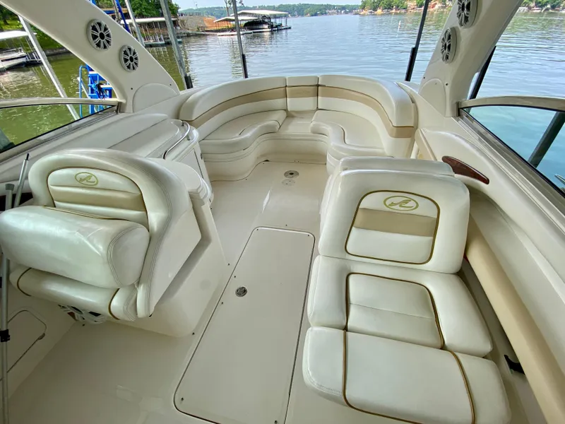 Slide: The Image of 2001 Sea Ray 290 Bowrider interior with cream leather seating, docked by a serene lake. - 20