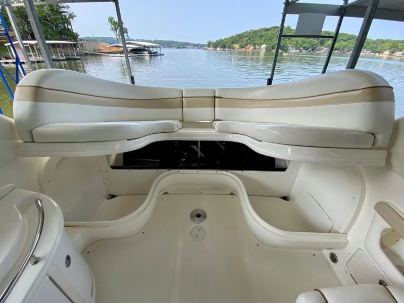 Slide: The Image of 2001 Sea Ray 290 Bowrider interior with spacious seating, docked by a scenic lake. - 29