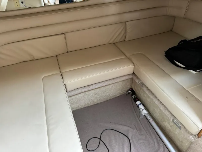 Slide: The Image of 1997 Sea Ray 330 Sundancer interior with beige leather seating and storage space. - 27