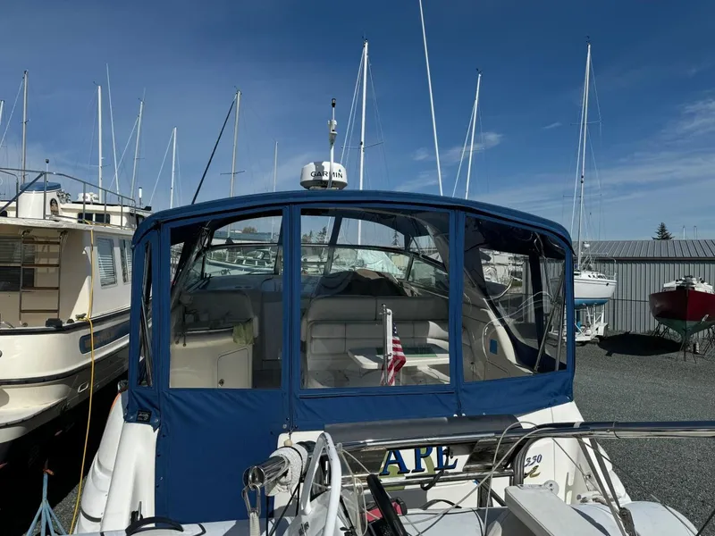 Slide: The Image of 1997 Sea Ray 330 Sundancer boat docked with blue canopy and American flag. - 5