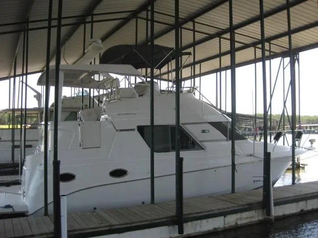 Slide: The Image of 1999 Silverton 352 Motor Yacht docked in a marina under a covered shelter. - 2