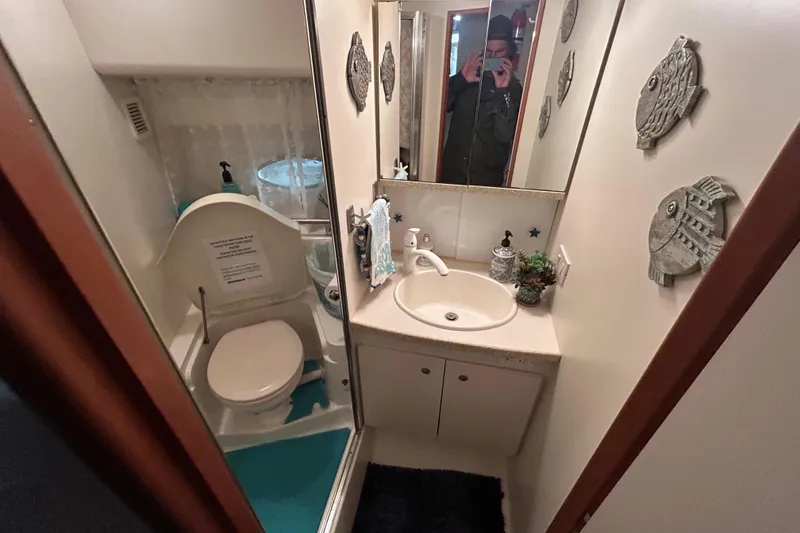 Slide: The Image of 1999 Silverton 352 Motor Yacht bathroom with sink, toilet, and decorative fish wall art. - 28