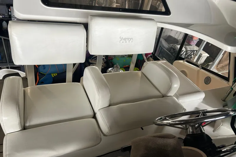Slide: The Image of 1999 Silverton 352 Motor Yacht interior with white seating and steering wheel. - 49