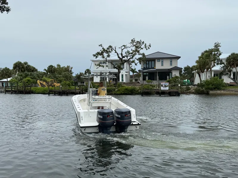 Slide: The Image of 2000 Contender 25 Open boat with dual engines on a calm waterway near houses. - 8
