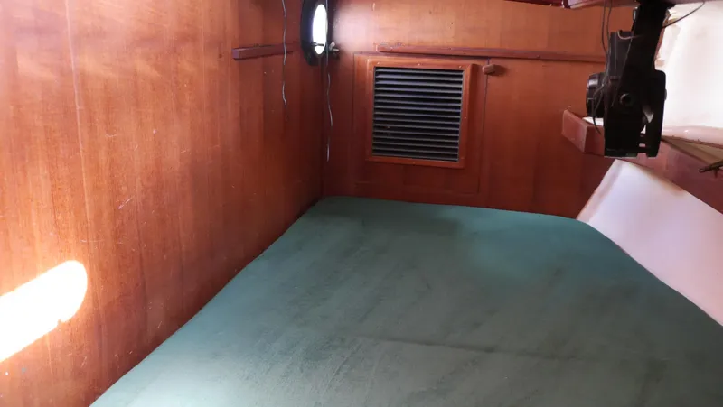 Slide: The Image of 1979 Tayana 37 cabin interior with wooden walls and green bedding. - 45