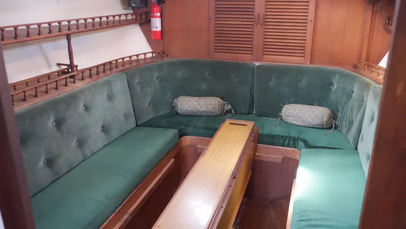 Slide: The Image of 1979 Tayana 37 yacht interior with green cushioned seating and wooden table. - 38