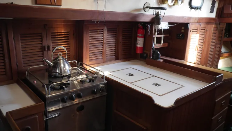 Slide: The Image of 1979 Tayana 37 yacht galley with stove, kettle, and wooden cabinetry. - 32