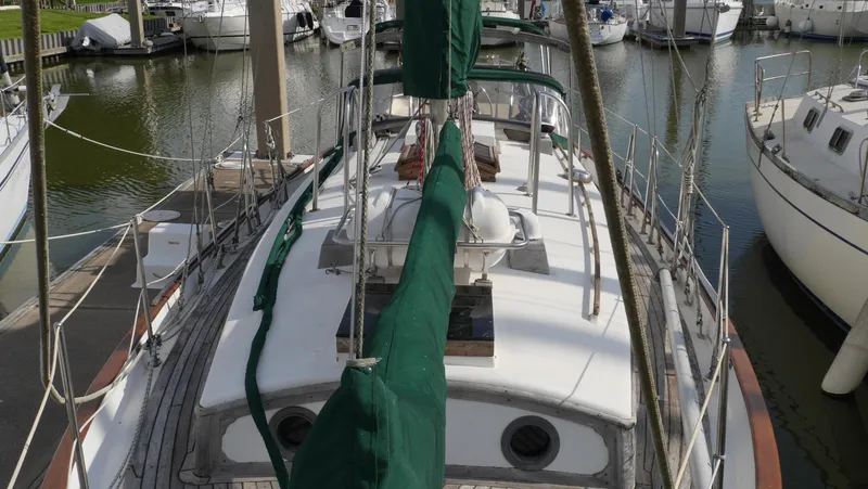 Slide: The Image of 1979 Tayana 37 sailboat docked in a marina, featuring green sail covers. - 19