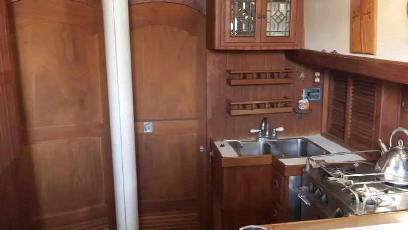 Slide: The Image of 1979 Tayana 37 yacht interior with wooden cabinetry, stainless steel sink, and stove. - 43