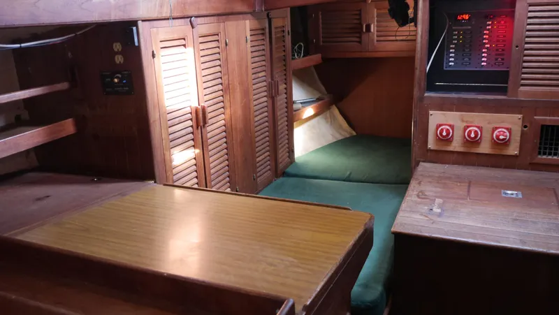 Slide: The Image of 1979 Tayana 37 yacht interior with wooden cabinetry and green cushions. - 25