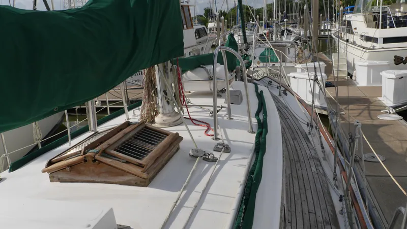 Slide: The Image of 1979 Tayana 37 sailboat docked at marina, featuring green covers and wooden deck details. - 13