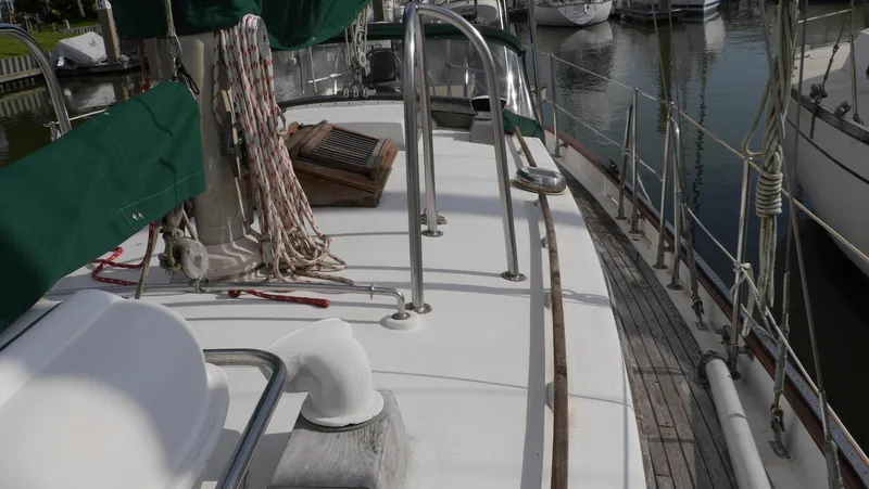 Slide: The Image of 1979 Tayana 37 sailboat deck with green covers, docked in a marina. - 15