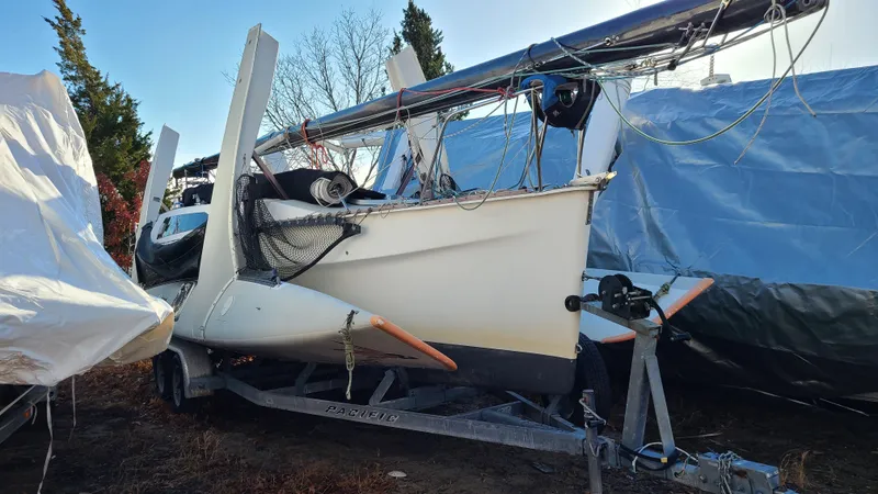 Slide: The Image of 1987 Corsair F-27 trimaran sailboat on trailer, partially covered, in outdoor storage. - 6