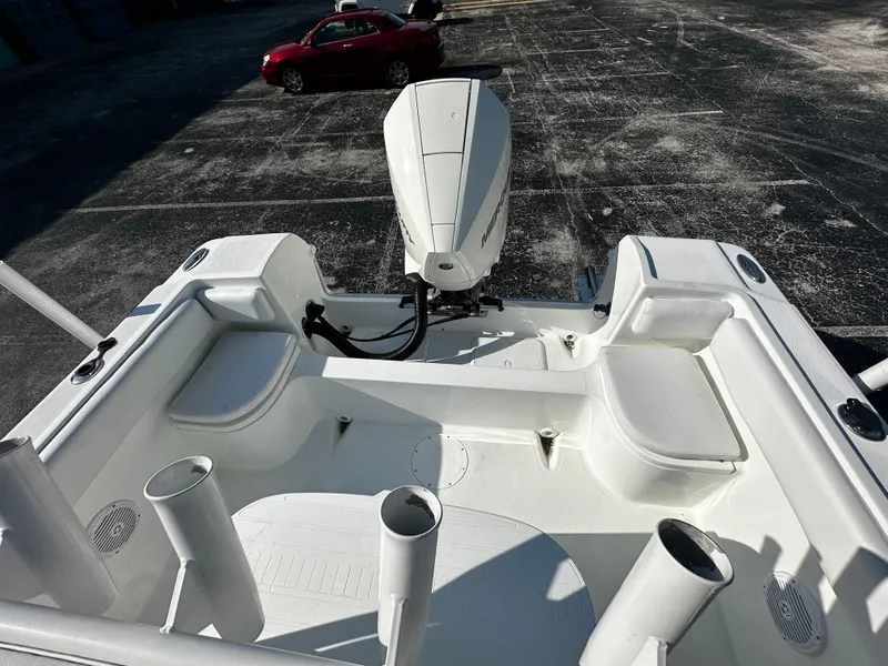 Slide: The Image of 2022 Clearwater 2300 CC boat interior with motor, parked in a lot. - 9