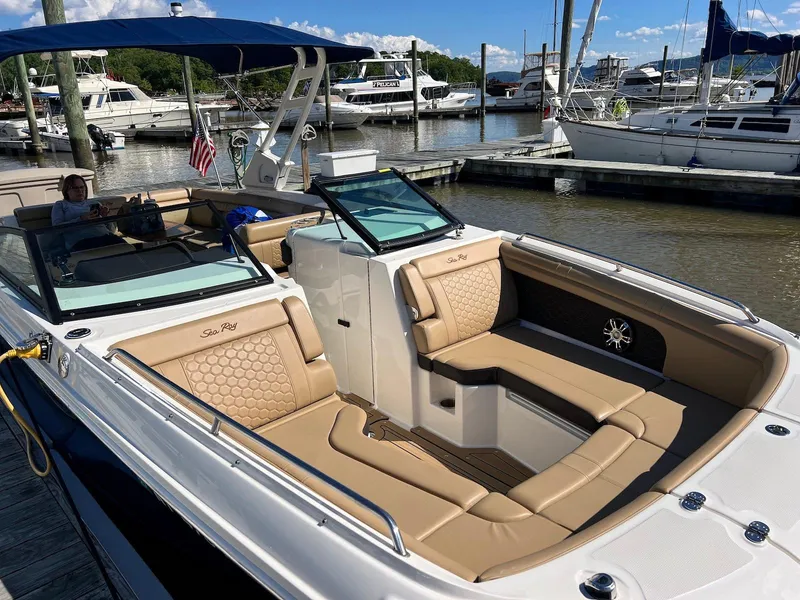 Slide: The Image of 2021 Sea Ray SDX 290 boat with tan seating, docked at a marina under blue skies. - 10
