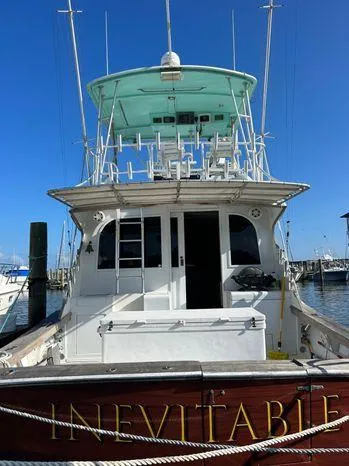 Slide: The Image of 1989 Post 43 Sport Fisherman boat docked, named "Inevitable," with clear blue sky background. - 3